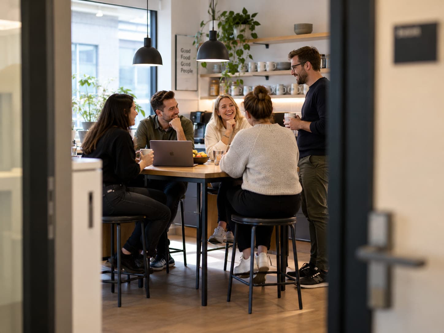 Ein Team sitzt zusammen an einem Tisch in einer Büroküche.